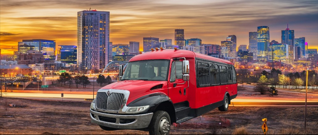 Downtown Denver skyline at night with a red and black bus in the foreground