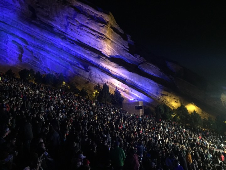 Red Rocks at night with blue lights and large crowd
