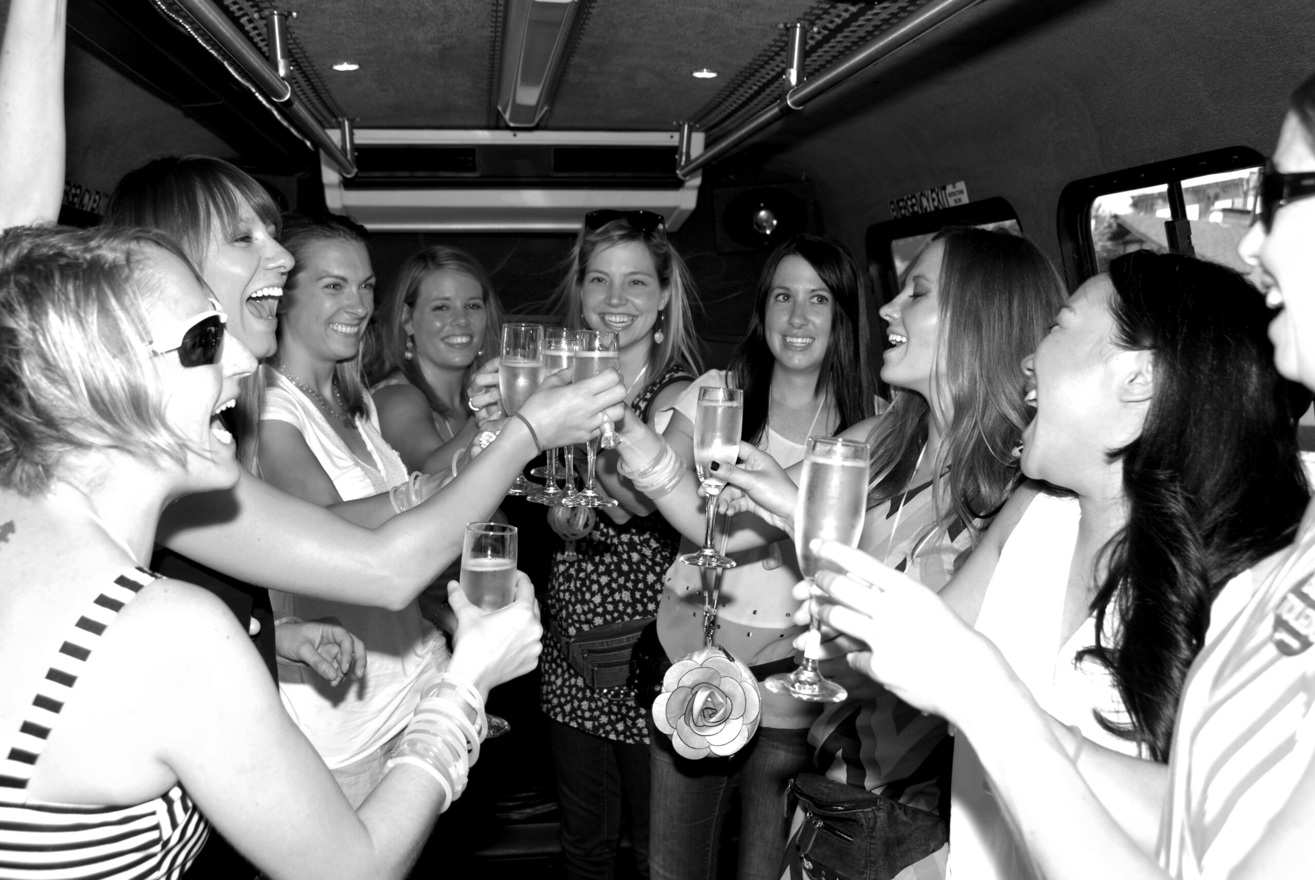 Bachelorette party smiling and toasting in a party bus
