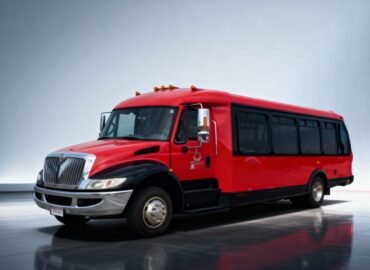 Contoured red limo bus with a dark grey reflective background